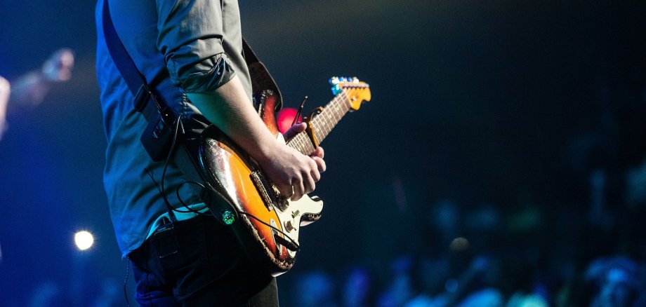 Ein Mensch spielt Gitarre auf einer Bühne